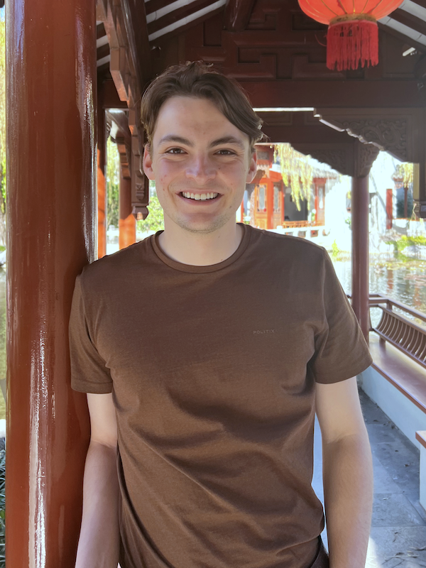 A picture of Andrew, smiling. Wearing a brown shirt.